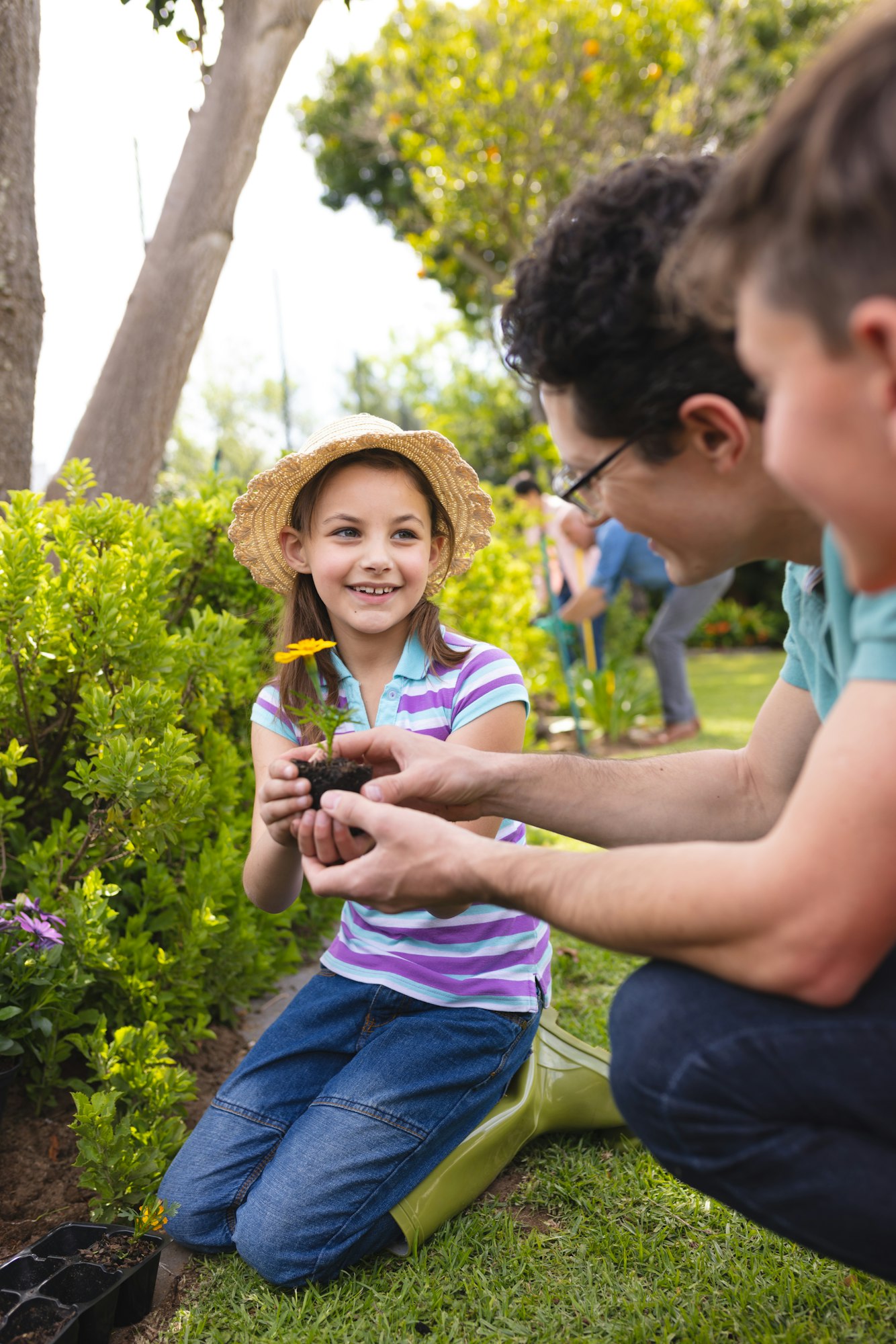 Vertical picture of caucasian family spending time together in the garden, planting