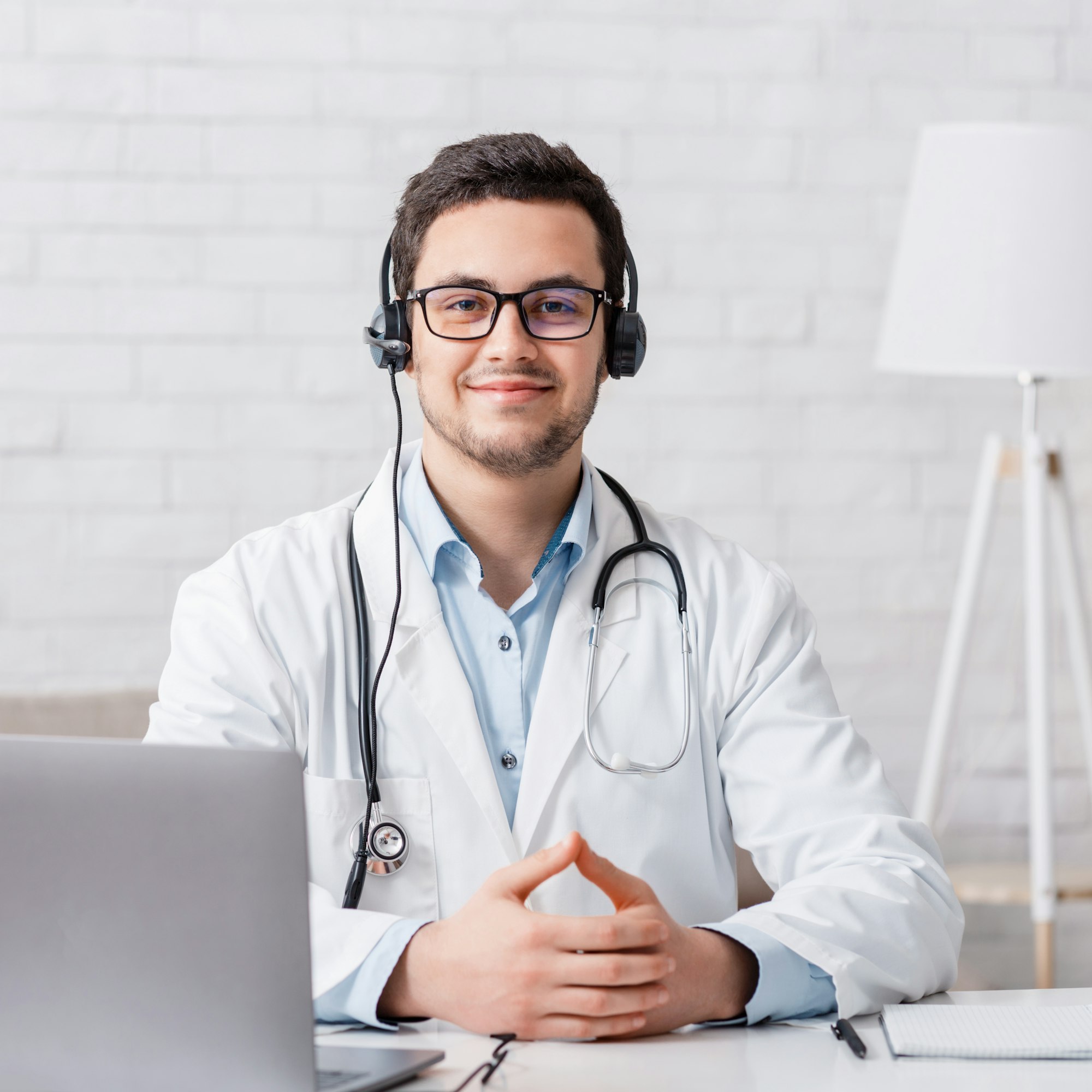 Work at home online. Doctor sits at table with laptop in interior